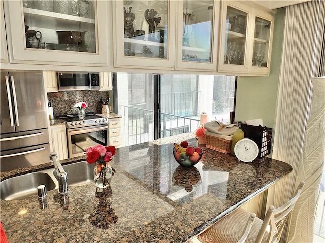 2601 E Ocean Blvd Unit 205, Long Beach, CA 90803 - kitchen featuring stainless steel appliances, cream cabinetry, dark stone countertops, and a kitchen breakfast bar
