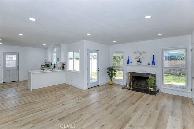 unfurnished living room with recessed lighting, baseboards, a tile fireplace, and light wood-type flooring