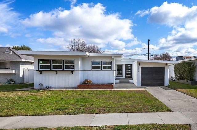 single story home featuring an attached garage, a front lawn, and driveway