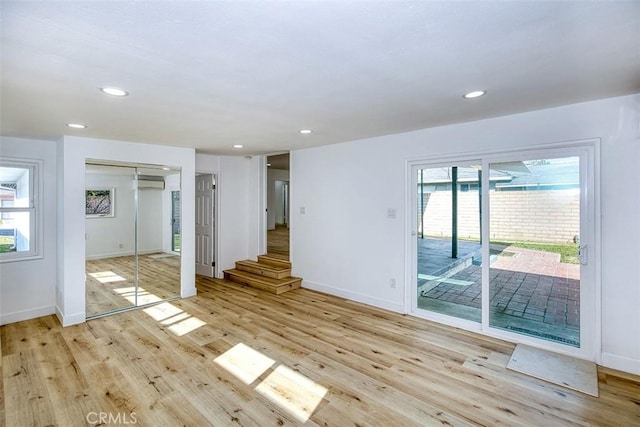 unfurnished living room with baseboards, a healthy amount of sunlight, and light wood-style flooring