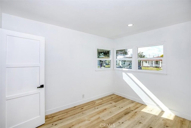 empty room with light wood-style floors, baseboards, and a healthy amount of sunlight
