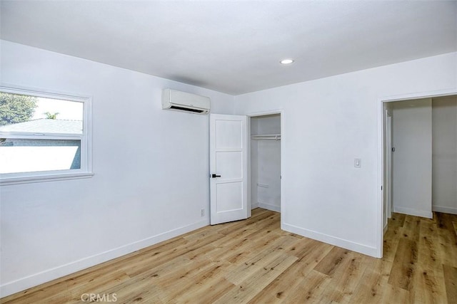 unfurnished bedroom with a closet, baseboards, a wall mounted air conditioner, recessed lighting, and light wood-type flooring
