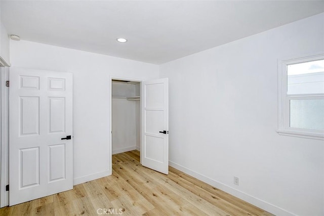 unfurnished bedroom with baseboards, a closet, recessed lighting, and light wood-style flooring