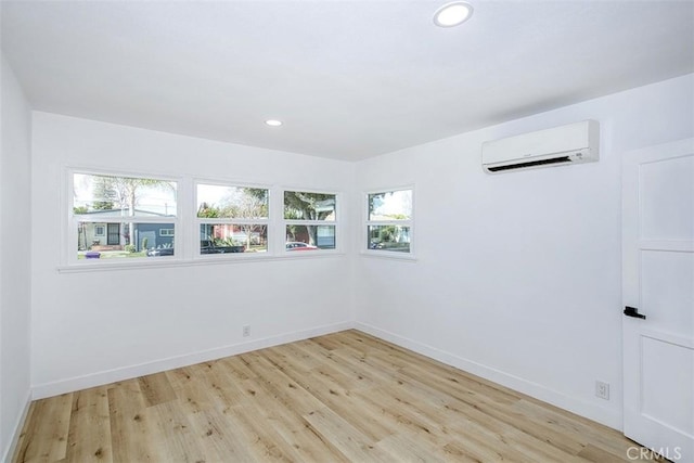 empty room featuring light wood-style floors, recessed lighting, baseboards, and a wall unit AC