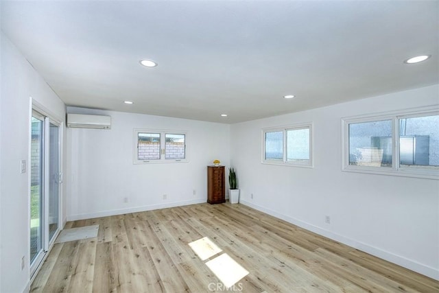 unfurnished room with recessed lighting, a wall mounted air conditioner, light wood-style floors, and baseboards