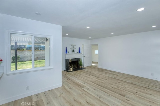 unfurnished living room featuring a fireplace, recessed lighting, baseboards, and light wood-type flooring