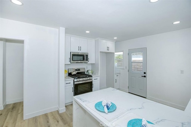 kitchen featuring light wood finished floors, stainless steel appliances, baseboards, recessed lighting, and white cabinetry