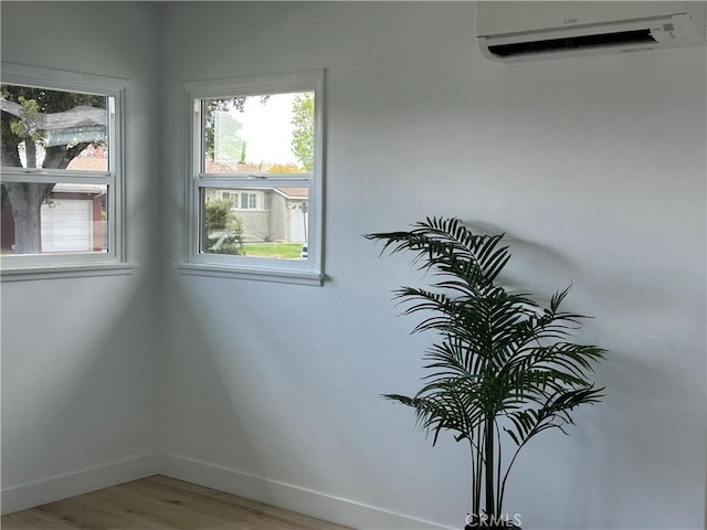 details featuring baseboards, a wall unit AC, and wood finished floors