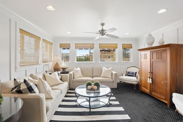 living area featuring dark carpet, ceiling fan, ornamental molding, and a decorative wall