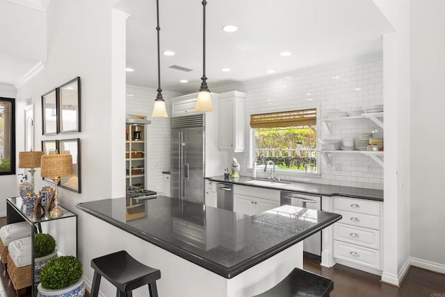 kitchen with white cabinetry, dark countertops, a sink, and stainless steel appliances