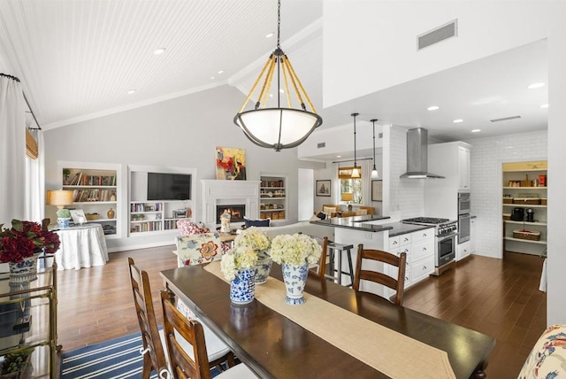 dining space with a lit fireplace, dark wood-style floors, visible vents, and high vaulted ceiling