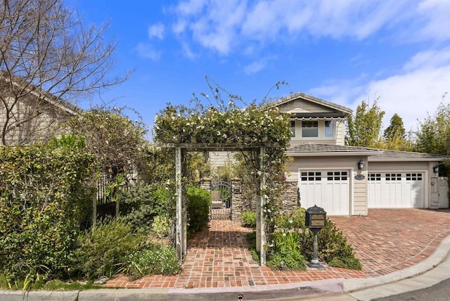 view of front of property featuring decorative driveway, a gate, and a garage