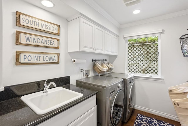 laundry area with ornamental molding, baseboards, separate washer and dryer, a sink, and cabinet space