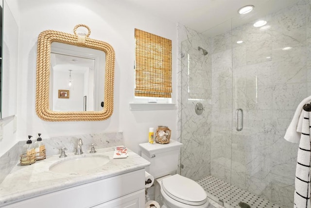 bathroom featuring toilet, vanity, and a marble finish shower