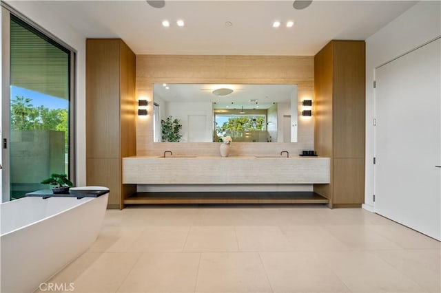 bathroom featuring a freestanding bath, recessed lighting, and double vanity