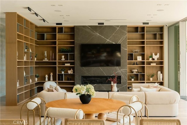 living area with a high end fireplace, wood finished floors, and built in shelves