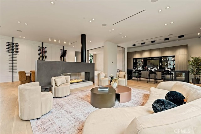 living room with light wood-style flooring, a glass covered fireplace, and recessed lighting