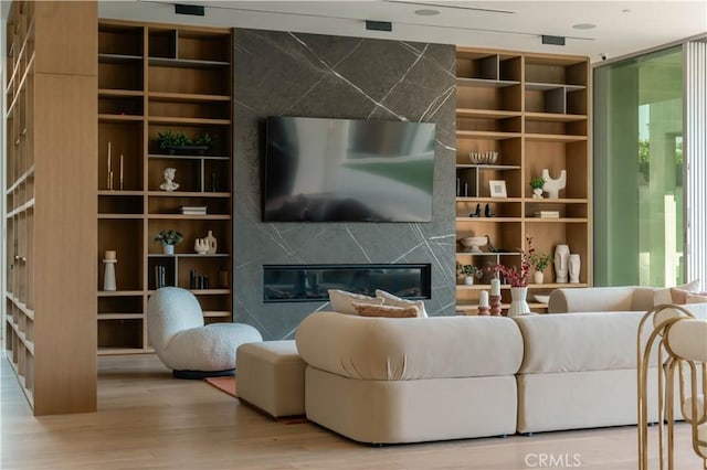living room featuring a wealth of natural light, a high end fireplace, wood finished floors, and built in features