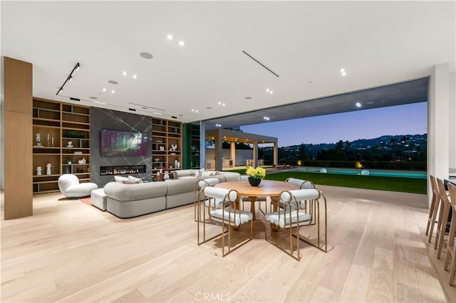 dining room with a glass covered fireplace, built in shelves, and wood finished floors