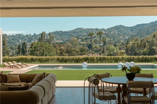 view of patio with a fenced in pool, a mountain view, an in ground hot tub, and a view of trees