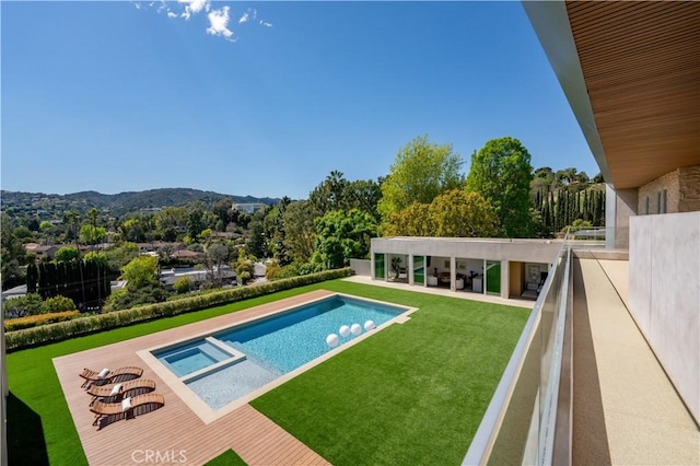 view of swimming pool with a lawn, a pool with connected hot tub, and a mountain view