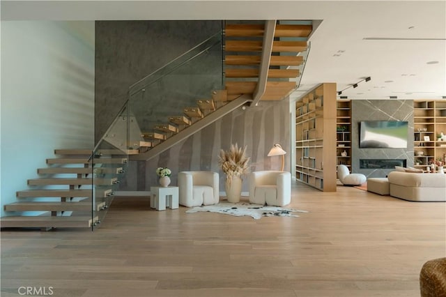 staircase with wood finished floors and a glass covered fireplace