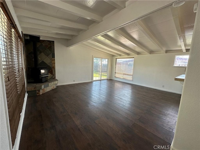 unfurnished living room with vaulted ceiling with beams, baseboards, a wood stove, and wood finished floors