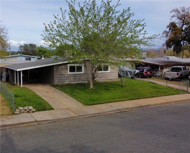 view of front of property featuring an attached carport, a front lawn, and concrete driveway