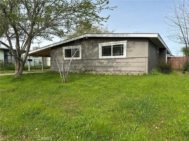 view of home's exterior featuring fence, a carport, and a yard