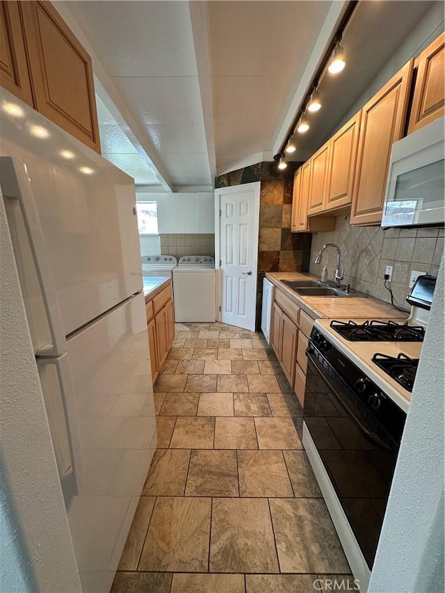 kitchen featuring decorative backsplash, light countertops, white appliances, a sink, and washer and dryer