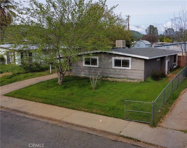 view of front of property with a front yard, central AC, and fence