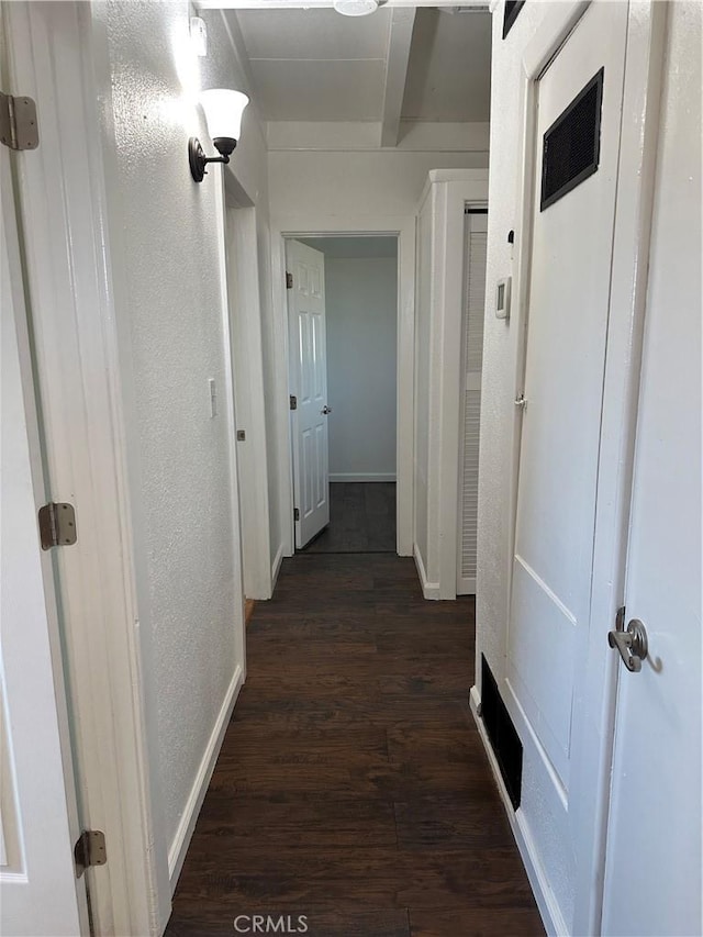 hallway featuring dark wood finished floors, baseboards, and a textured wall