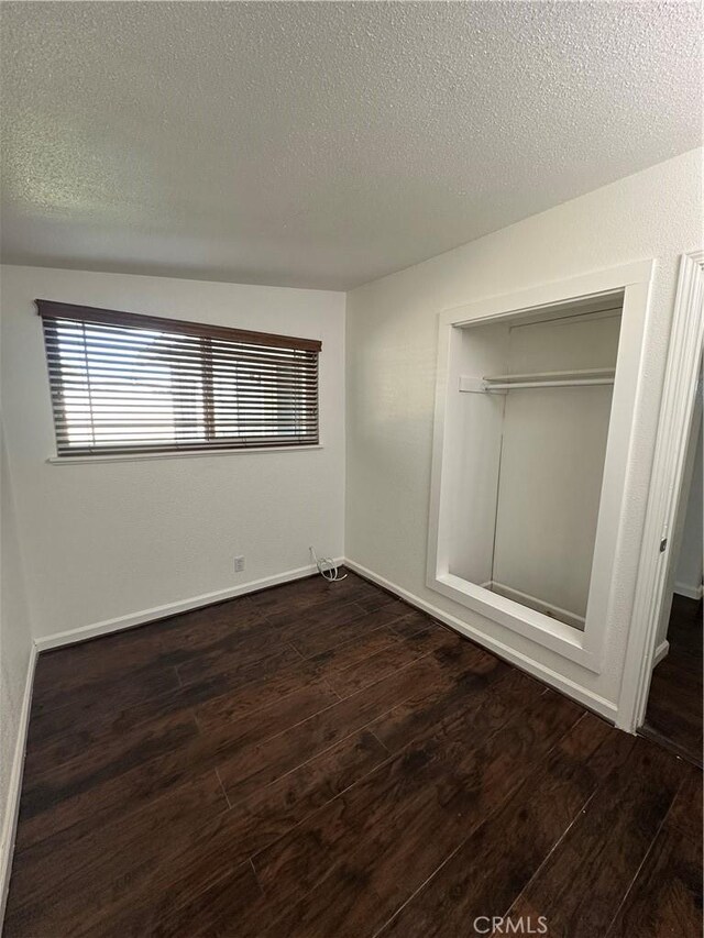 unfurnished bedroom with baseboards, a closet, wood finished floors, and a textured ceiling