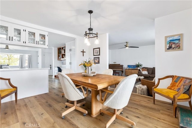dining space featuring ceiling fan with notable chandelier and light wood finished floors