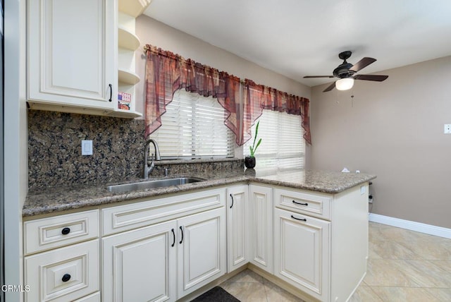 kitchen with white cabinetry, backsplash, open shelves, a ceiling fan, and a sink