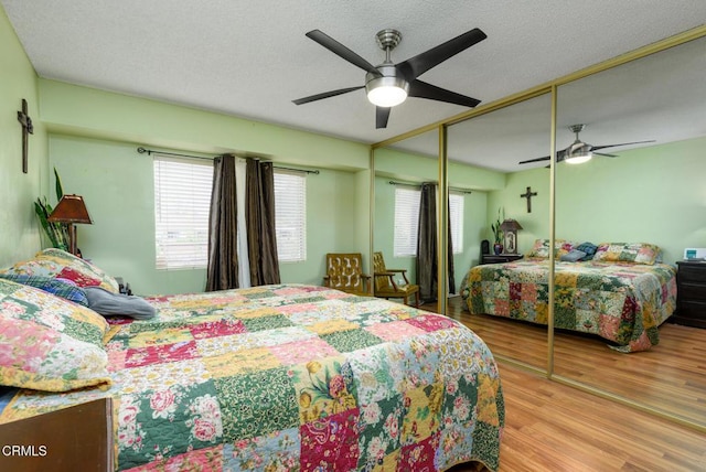 bedroom with ceiling fan, multiple windows, wood finished floors, and a textured ceiling