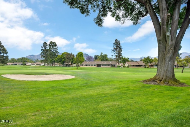 view of property's community featuring view of golf course, a residential view, a mountain view, and a lawn