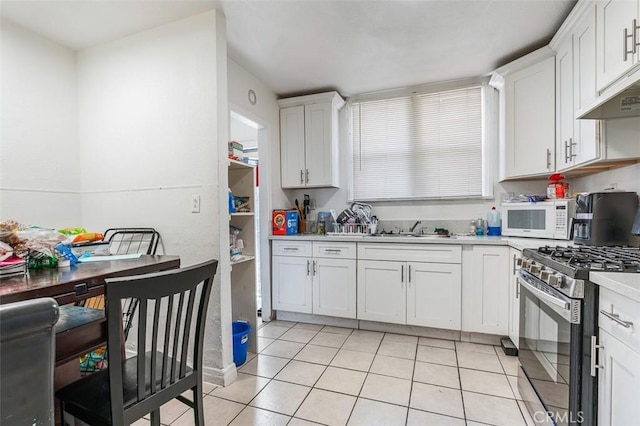 961 W 47th St, Los Angeles, CA 90037 - kitchen featuring gas range, white microwave, a sink, light countertops, and white cabinetry