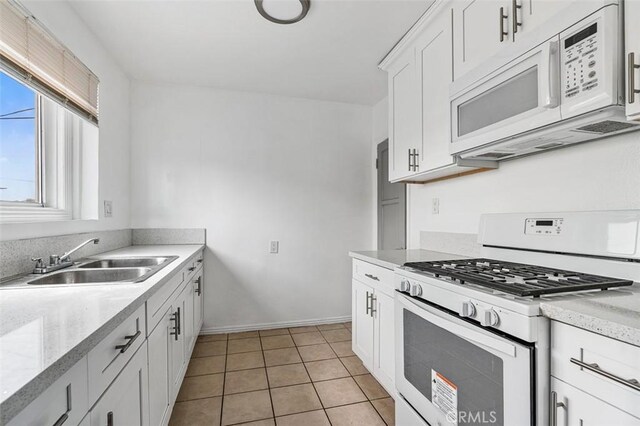 961 W 47th St, Los Angeles, CA 90037 - kitchen with white appliances, a sink, white cabinets, light tile patterned floors, and baseboards