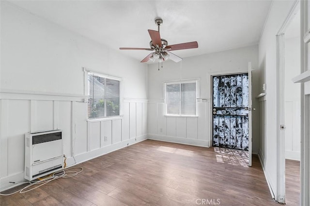 961 W 47th St, Los Angeles, CA 90037 - unfurnished living room featuring heating unit, wood finished floors, a ceiling fan, a decorative wall, and wainscoting