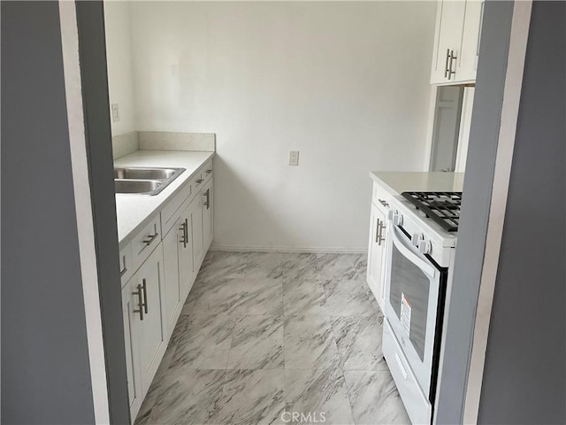961 W 47th St, Los Angeles, CA 90037 - kitchen featuring white gas stove, light marble finish floors, light countertops, a sink, and white cabinets