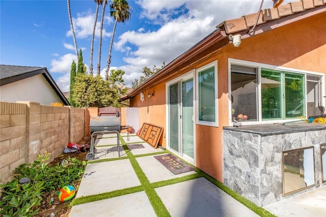 view of side of property with stucco siding, a patio area, and a fenced backyard
