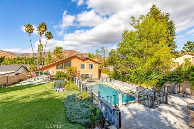 view of swimming pool with a yard, fence, a fenced in pool, a patio, and a mountain view