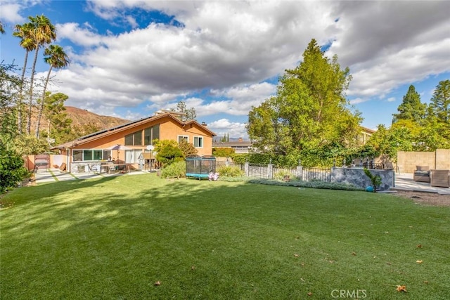 view of yard featuring a patio, a trampoline, and a fenced backyard