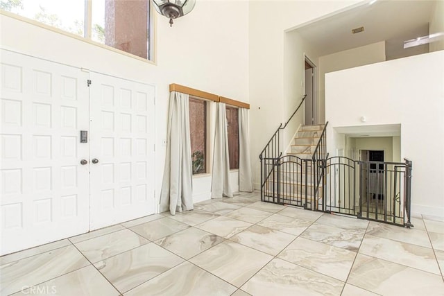 entrance foyer featuring visible vents, stairs, a high ceiling, and marble finish floor