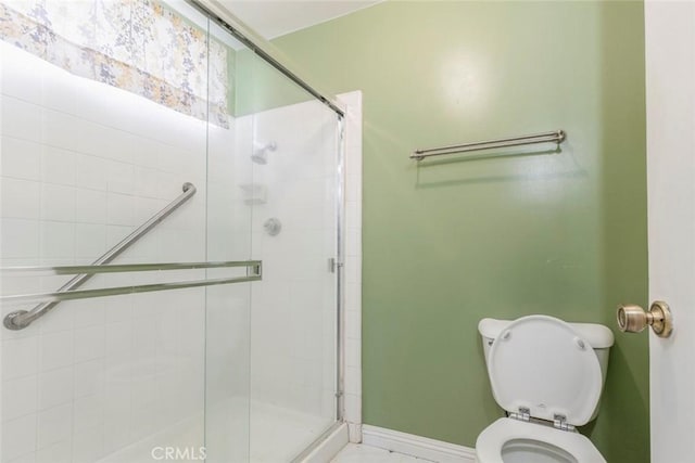 full bathroom with baseboards, a stall shower, and toilet