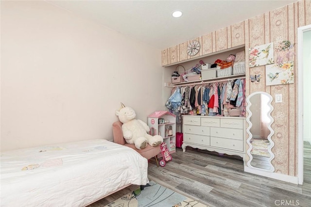 bedroom featuring recessed lighting, wood finished floors, and a closet