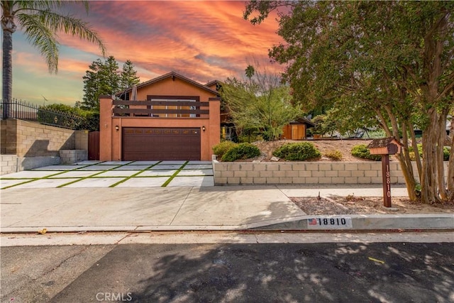 view of front of property with fence, concrete driveway, and stucco siding