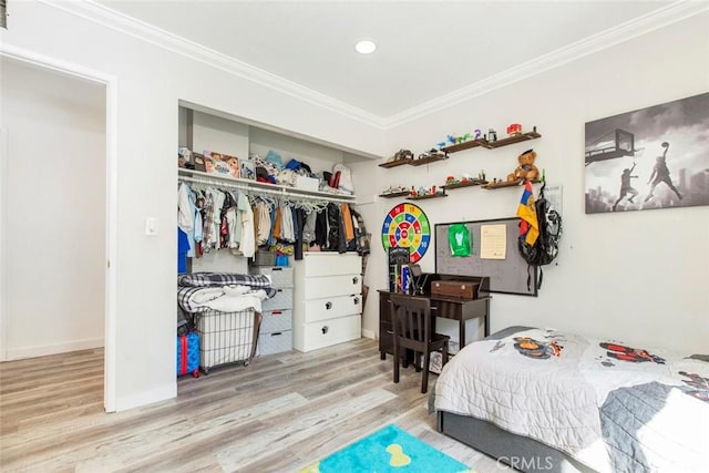 bedroom featuring baseboards, ornamental molding, wood finished floors, and a closet