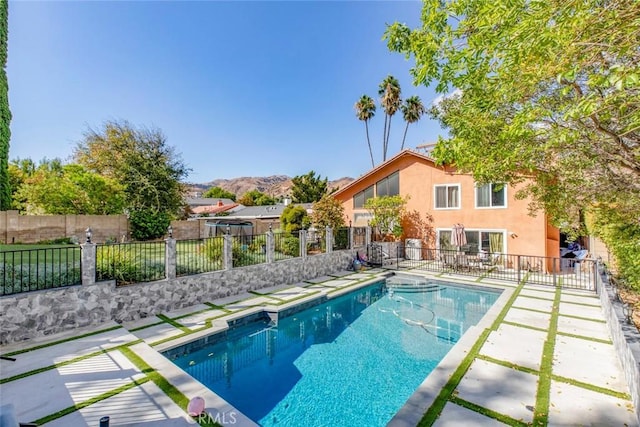 view of pool featuring a mountain view, a fenced in pool, a fenced backyard, and a patio area
